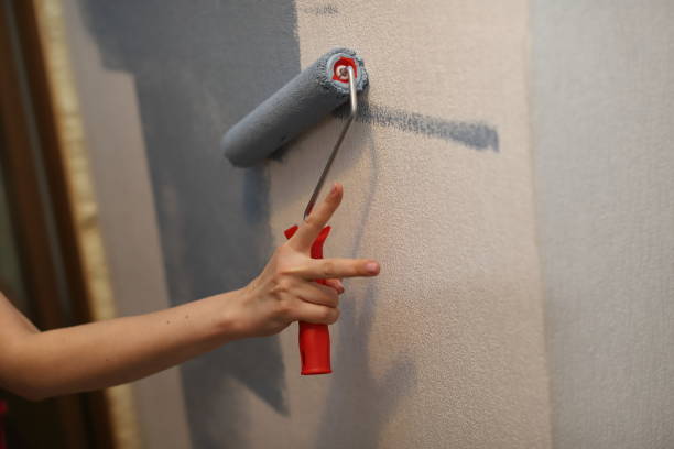 istock young girl paints a wall with blue paint roller 1244455741