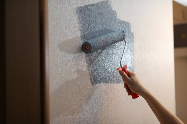istock young girl paints a wall with blue paint roller 1244458942