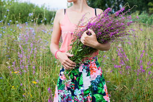 A young girl holding a bouquet of wildflowers in her hands.