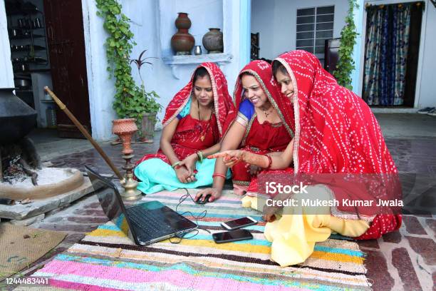 Traditional Indian Young Married Women Working In Traditional Kitchen On Laptop Stock Photo - Download Image Now