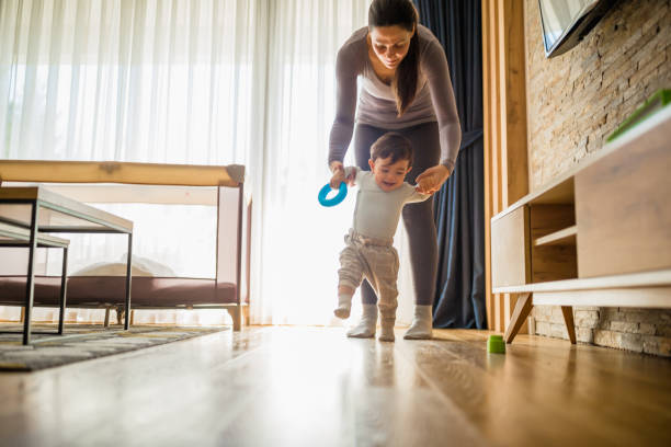 Baby's First Steps Mother assisting her baby boy making first steps. They are in their home during the isolation period. Belgrade, Serbia first steps stock pictures, royalty-free photos & images