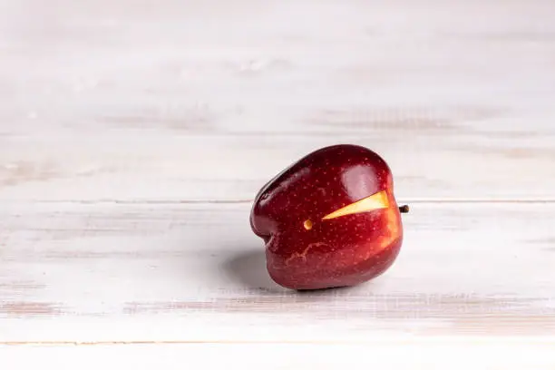 Close-up image of a vibrant shiny red coloured juicy apple precisely carved with exclamation mark sigh placed on white bleached pine floor boards surface in studio. Ideal for many concept with plenty of copy space for your message and ideas: Ripe Fruit, Healthy Lifestyle, Warning sigh, Healthcare And Medicine, Carving - Craft Product, etc. Shot on Canon EOS R with premium lens for highest quality.