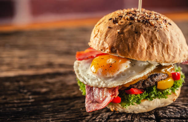 istock Detail of a burger with beef, cheese, egg, bacon, salad, peppers in a rustic environment. 1244495578