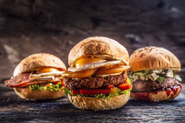 istock Cheeseburger, chicken burger and beef burger with blue cheese and cranberry sauce in a rustic surroundings. 1244497236