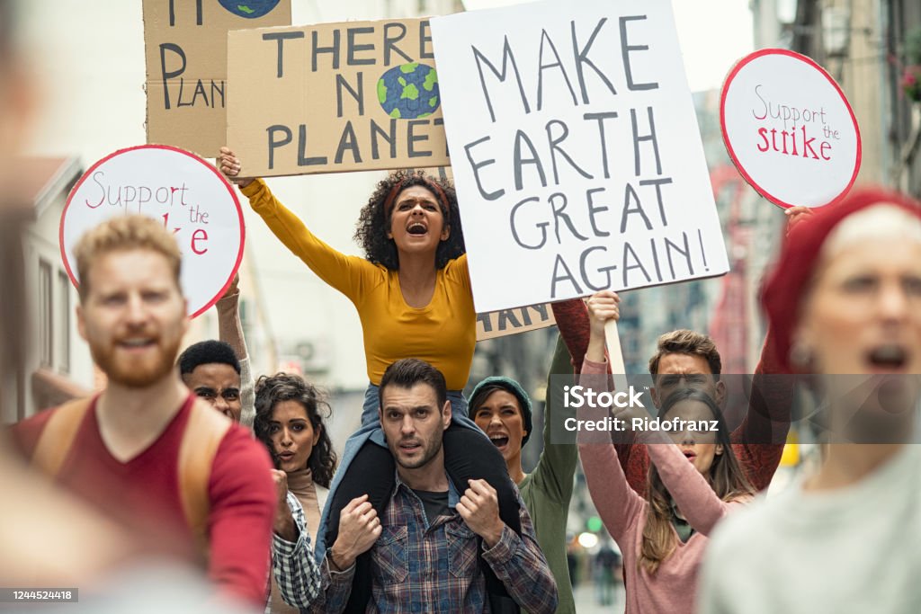 Climate change protest Group of young people demonstrate against climate change. Angry women and men strike with boards and signs in support of our planet. Group of activists protest and march to save the planet. Protest Stock Photo