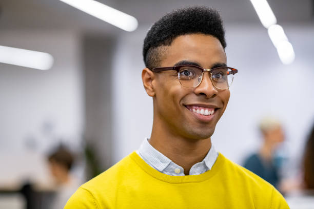 Successful young african man smile Young african businessman smiling while standing in co-working office. Close up face of successful black man looking away and laughing. Portrait of university nerd student with big grin. black nerd stock pictures, royalty-free photos & images