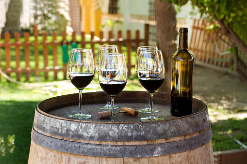 Red wine glasses and a bottle on a barrel in the garden