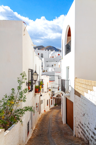 Whitewashed narrow street in Mojacar, Algeria, Spain with colourful Bougainvillea flowers.