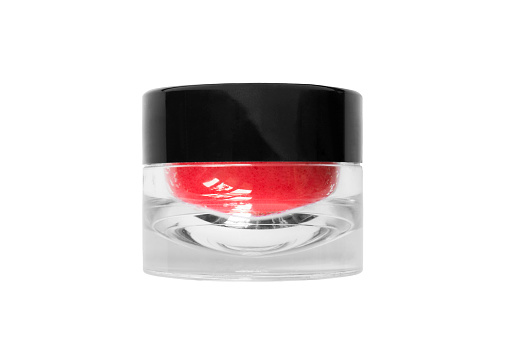 Red lip balm in glass jar on white background