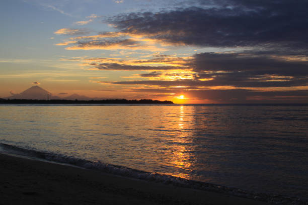 istock Sun shining from behind clouds with island silhouette 1244544039