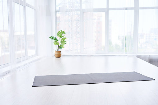 yoga room with big light window in modern flat. Yoga mat on the floor, no people