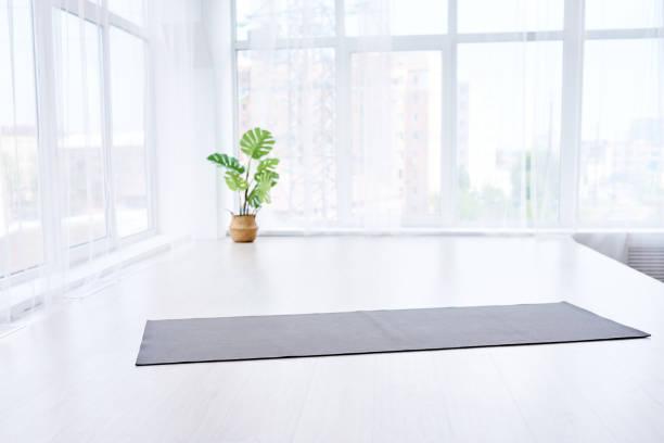 yoga room with big light window in modern flat. Yoga mat on the floor, no people yoga room with big light window in modern flat. Yoga mat on the white floor, no people exercise room photos stock pictures, royalty-free photos & images
