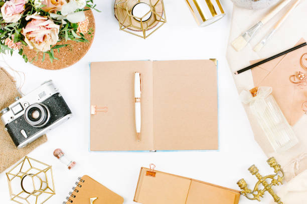 istock An elegant workspace of creative man in vintage style with notebook, film camera, envelope, candlestick, vase, flowers. Flat lay, top view 1244567182