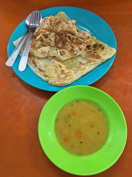 Flatbread Roti canai, also known as Roti cane, Roti parotta served with dal on wooden table Top view of flatbread Roti canai, also known as Roti cane, Roti parotta served with dal on wooden table roti canai stock pictures, royalty-free photos & images