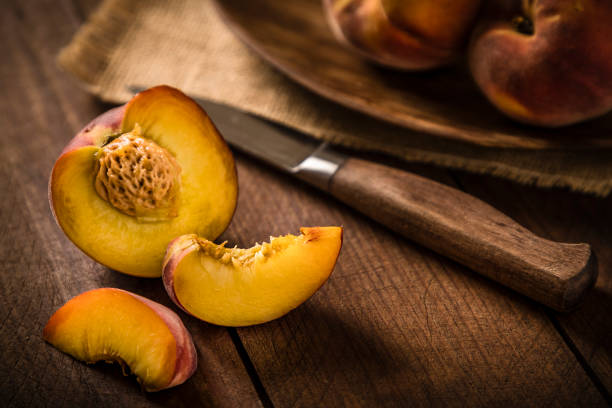 istock Sliced peach with a kitchen knife on a wooden table 1244626099