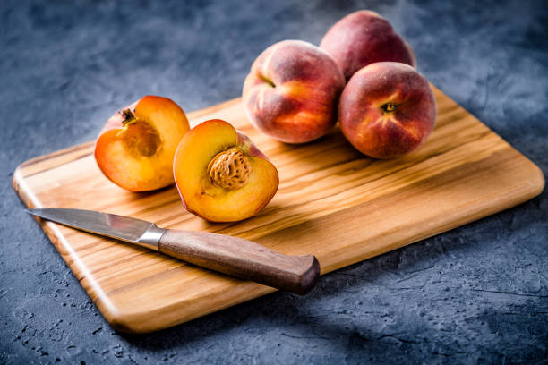 istock Whole and sliced peaches with a kitchen knife on a cutting board 1244626107