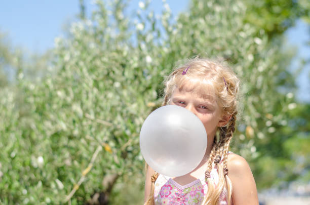 маленький ребенок с огромным пузырем от жевательной резинки - chewing gum bubble blowing little girls стоковые фото и изображения