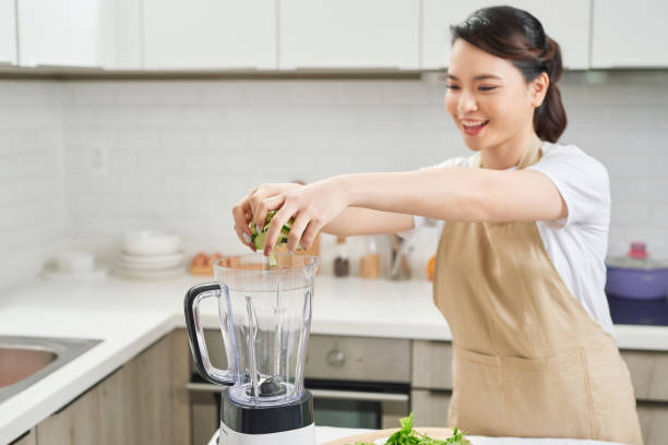 istock Vegetable smoothie woman blending green smoothies with blender home in kitchen. 1244632755