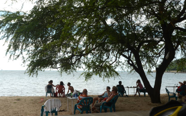 A group of tourists sit around enjoying a sunset on the beach in Dili City, Timor Leste on February 5, 2012