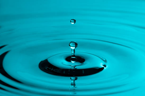 istock Water drop falling through the air. Small round ripples in a smooth surface and a reflection 1244657151
