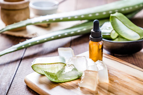 Aloe vera crystals for a skin care High angle view of some aloe vera crystals with a cosmetic dropper on a wooden board. A black bowl full of sliced aloe vera leaves is defocused on the background.  Predominant color are green and brown. Studio shot taken with Canon EOS 6D Mark II and Canon EF 24-105 mm f/4L tincture photos stock pictures, royalty-free photos & images