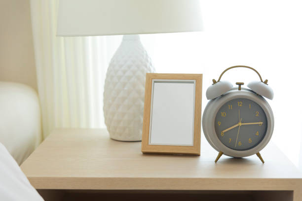 istock Alarm clock on the table beside white cozy bed in bedroom. 1244686566