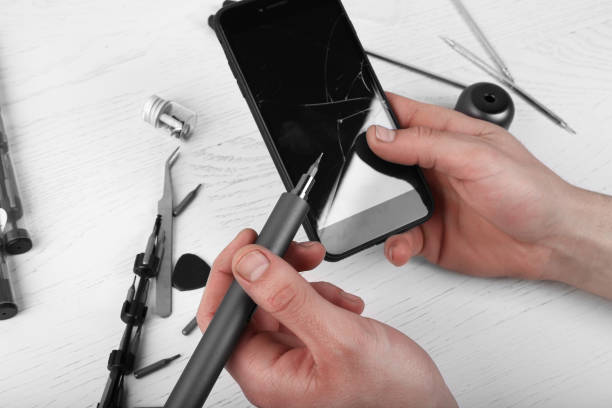 istock Repairman workplace with phone and special tools. Disassembled smartphone with disassembling instruments and repairer hands on white wood background. Electronics repair service 1244690784