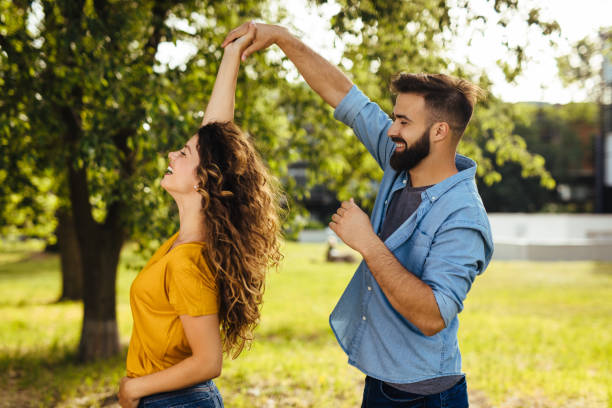 Young couple spending day in nature holding hands and dancing