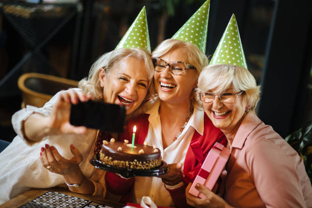 istock Senior ladies taking selfie while celebrating birthday in cafe 1244710247