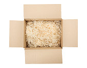 Top view of open cardboard box with shredded wood excelsior for filling inside. Using natural sustainable material for wrapping or products background. Isolated on white, studio shot.
