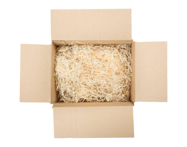 Top view of open cardboard box with shredded wood excelsior for filling inside. Using natural sustainable material for wrapping or products background. Isolated on white, studio shot. Top view of open cardboard box with shredded wood excelsior for filling inside. Using natural sustainable material for wrapping or products background. Isolated on white, studio shot. stuffed photos stock pictures, royalty-free photos & images