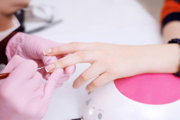 istock Closeup young well-groomed female hands. Manicurist doing professional manicure. Master applies nail polish to client. 1244733708