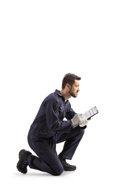 istock Auto mechanic worker in a uniform kneeling and writing a document 1244738693