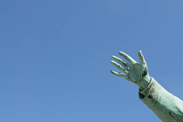 Reaching Hand of an old sculpture against a clear blue sky (providing plenty of space for text or copy!). statue of hans christian andersen stock pictures, royalty-free photos & images