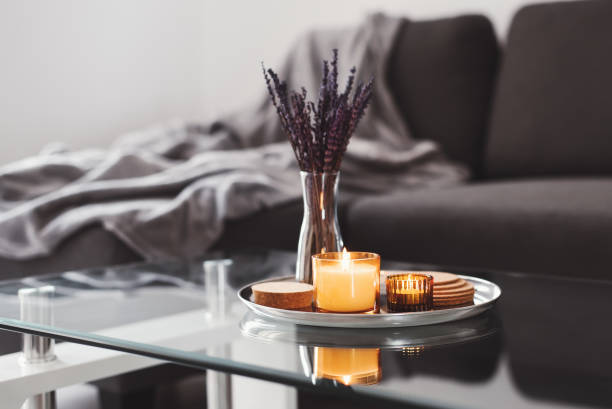 couchtisch-design-idee: aromakerzen und getrocknetes lavendelstrauß auf einem metalltablett, sofa mit grauer decke auf dem hintergrund. einfache skandinavische wohnkultur. hygge-konzept - vase fotos stock-fotos und bilder