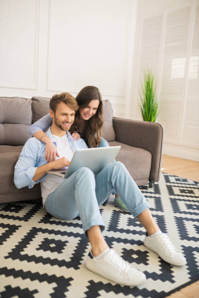 istock Young couple in denim sitting on a floor watching something online 1244753937