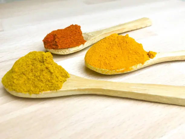 Spices on teaspoons, curry, turmeric, paprika.