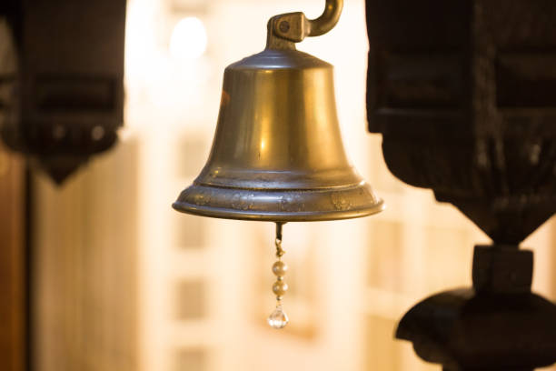 Brass bell with ornate chime lit up by background lighting