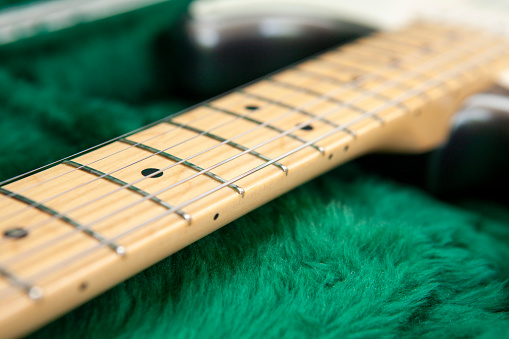 A closeup of Electric guitar bridge and strings against blurred background