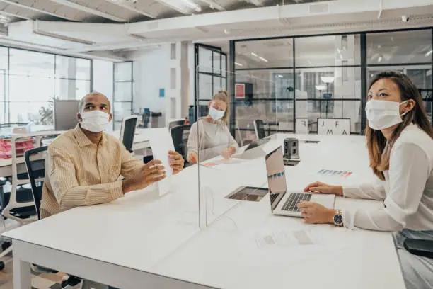 Photo of Businesspeople working at office with glass partition dividing them