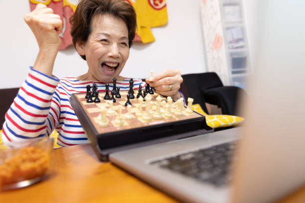 Senior woman playing chess on video call Senior woman playing chess on video call computer chess stock pictures, royalty-free photos & images
