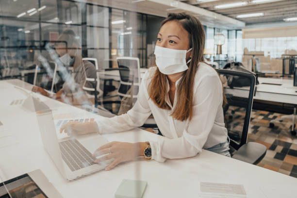 istock Businesspeople working at office with glass partition dividing them 1244799450