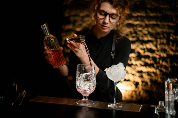 istock young nice girl barman pours drink from jigger into mixing cup. 1244799457