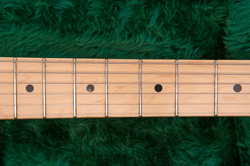 Close-up of an electric guitar neck in a green fur-lined guitar case