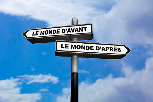 Two direction signs, one pointing left and the other one, pointing right, with written in them in French : Le monde d'avant / Le monde d'après, meaning in English: The world of before / The world of after.