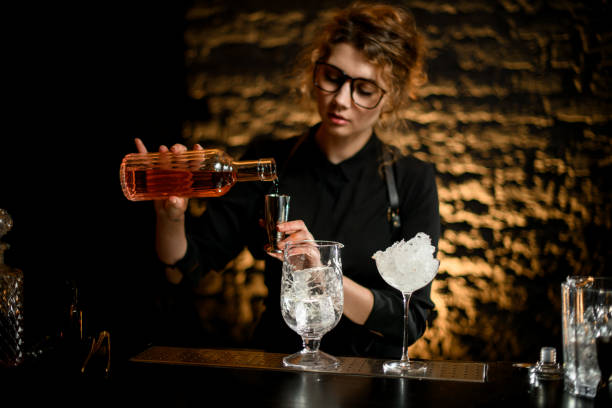 istock young nice girl barman pours drink from bottle into jigger. 1244813519