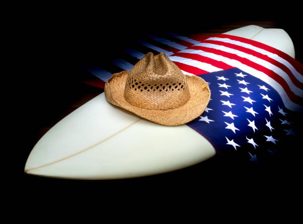 istock USA Flag on a white surfboard with a straw hat, black background, and a guitar. 1244821052