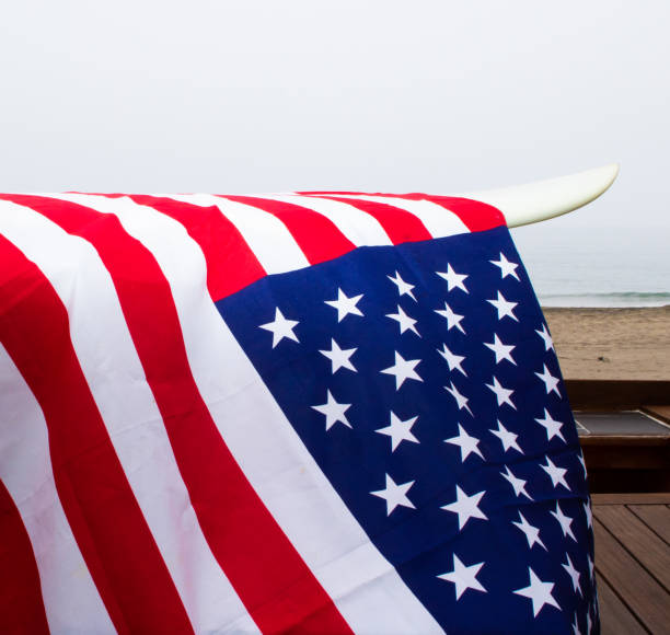 istock USA Flag on a white surfboard with a straw hat, black background, and a guitar. 1244821057