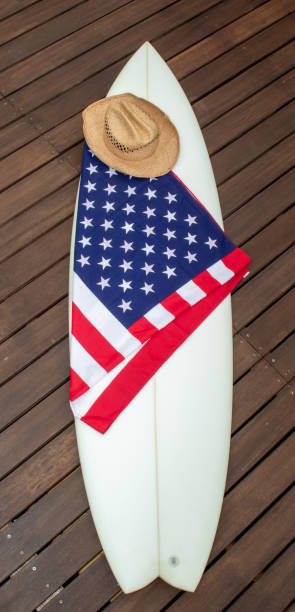 istock USA Flag on a white surfboard with a straw hat, black background, and a guitar. 1244821062