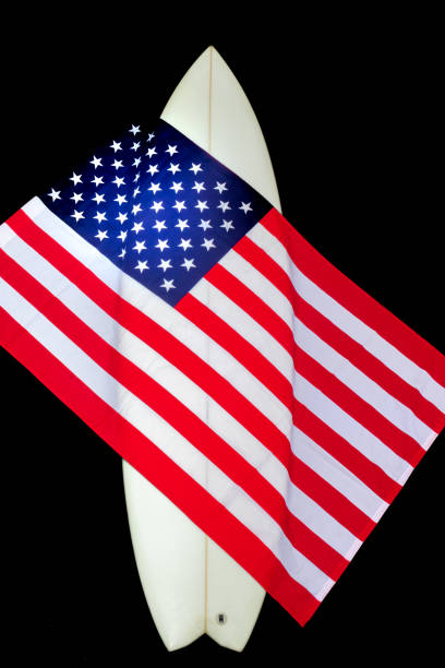 istock USA Flag on a white surfboard with a straw hat, black background, and a guitar. 1244821138